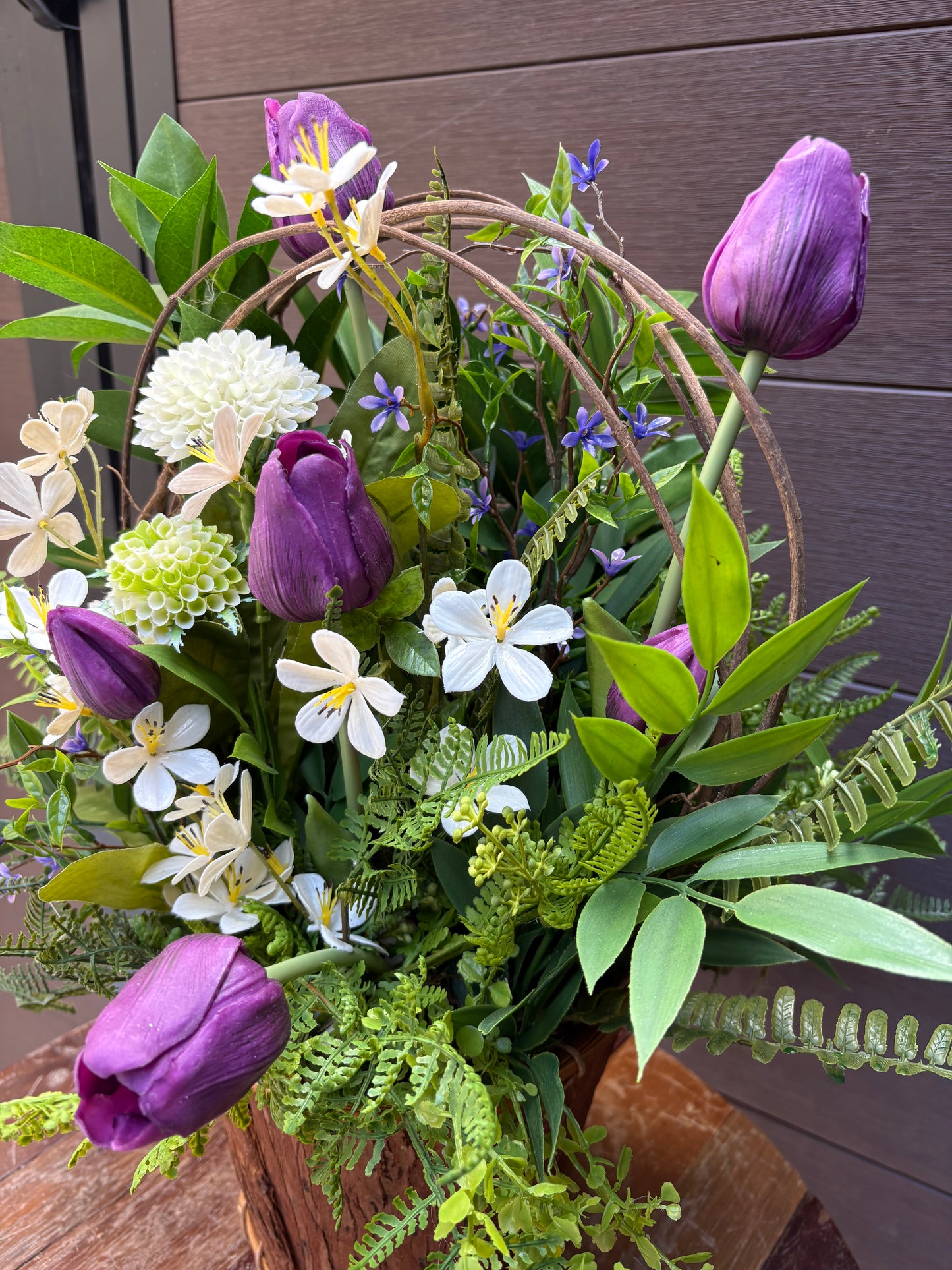 Arrangement floral en pot effet bois avec tulipes mauves et verdure champêtre