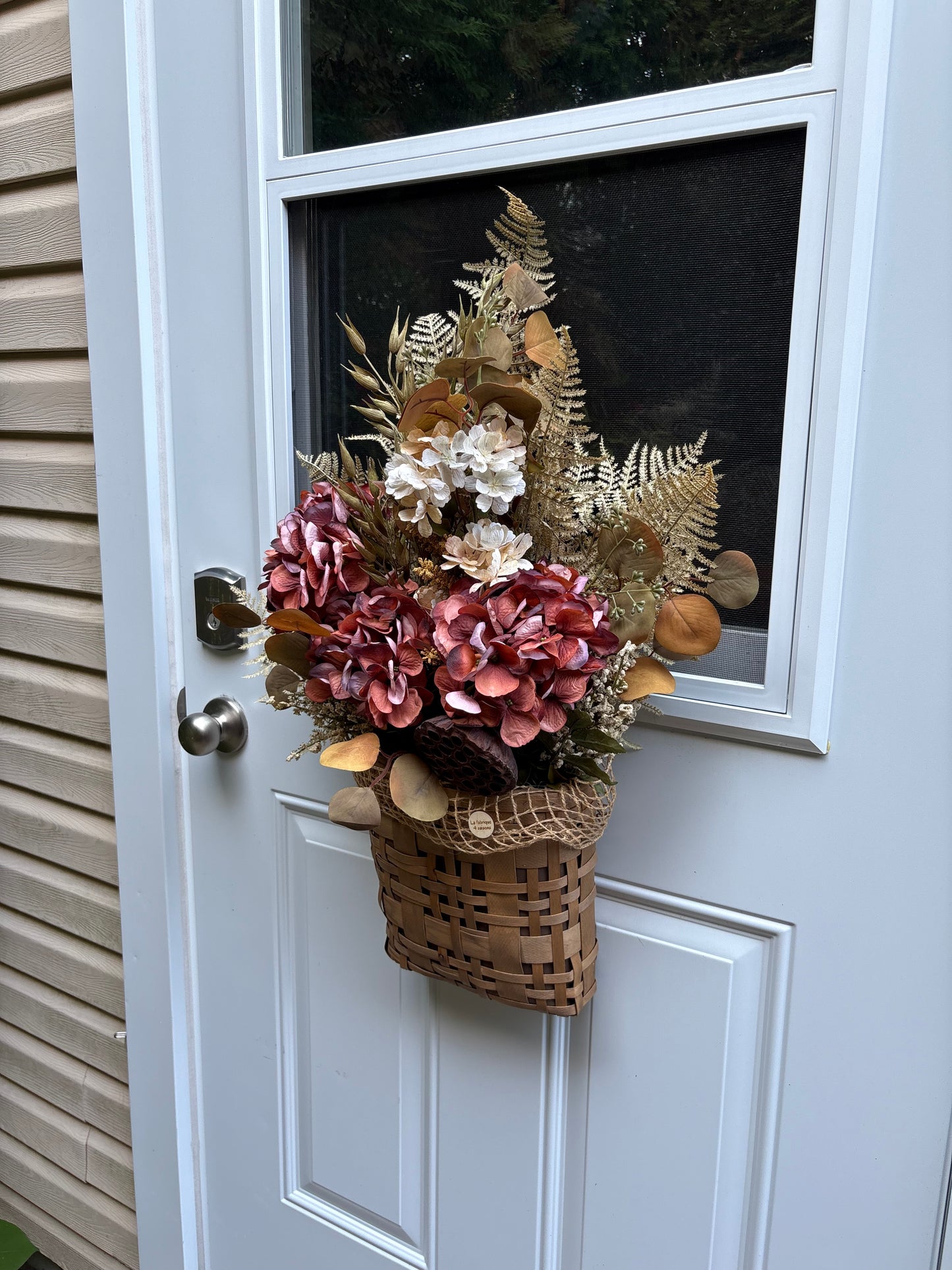 Panier floral d’automne suspendu à une porte d’entrée
