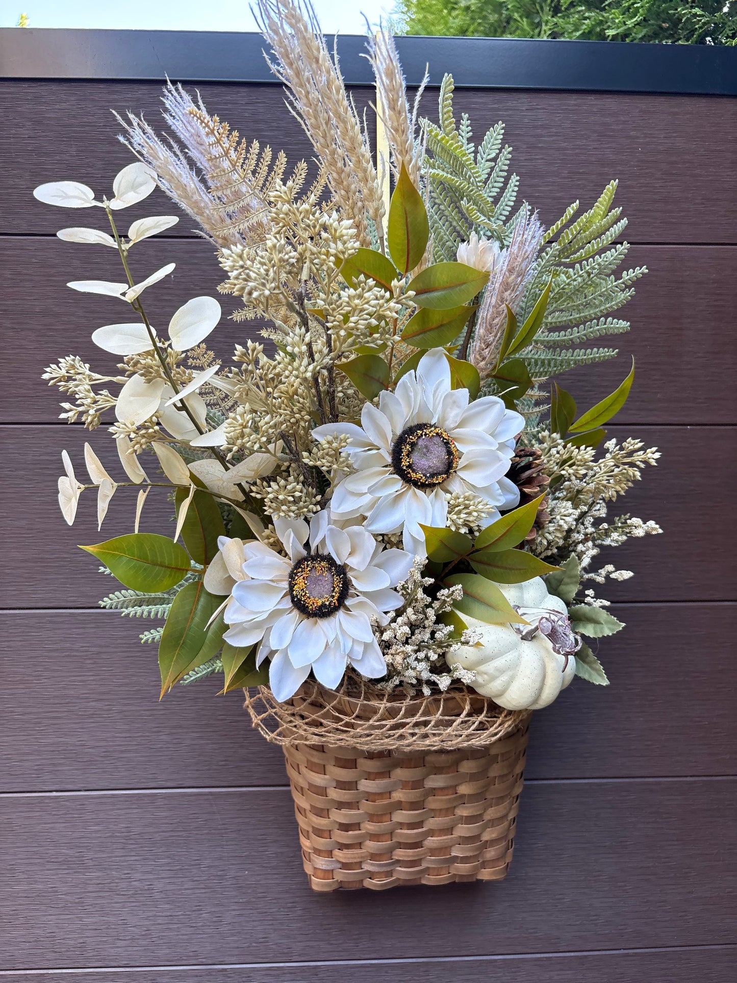 Composition florale automnale en panier d’osier pour porte ou mur couvert