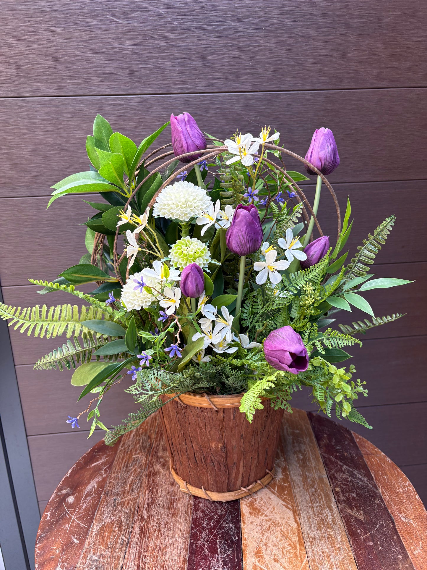 Arrangement floral en pot effet bois avec tulipes mauves et verdure champêtre