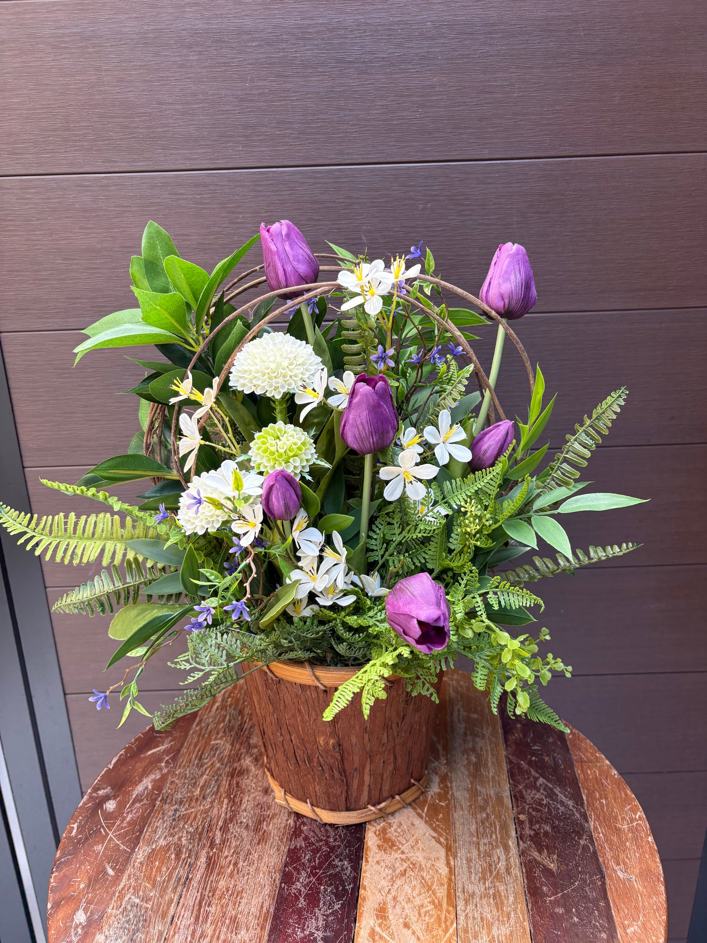 Arrangement floral en pot effet bois avec tulipes mauves et verdure champêtre