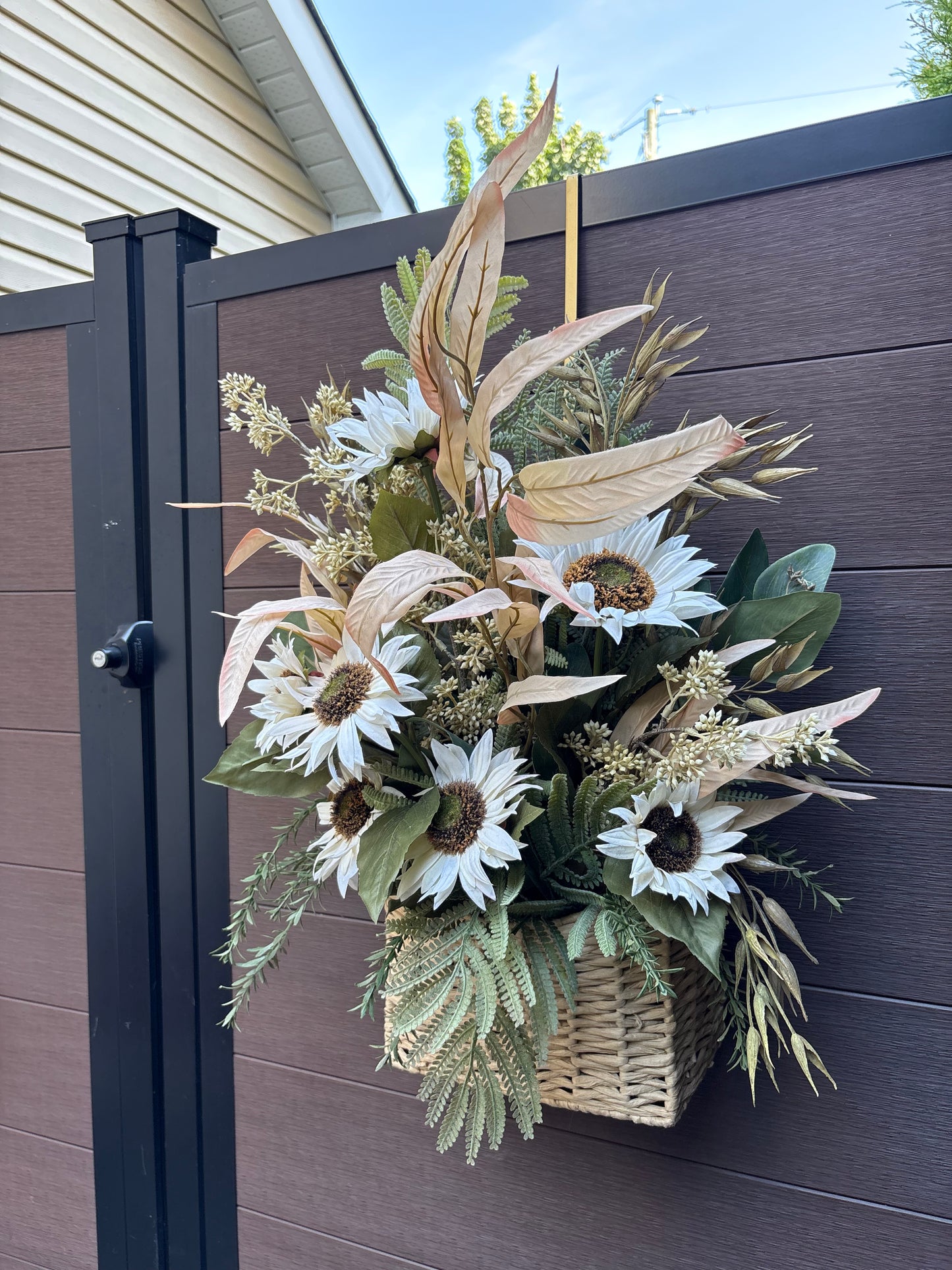 Détail des tournesols blancs et des feuillages artificiels du panier floral