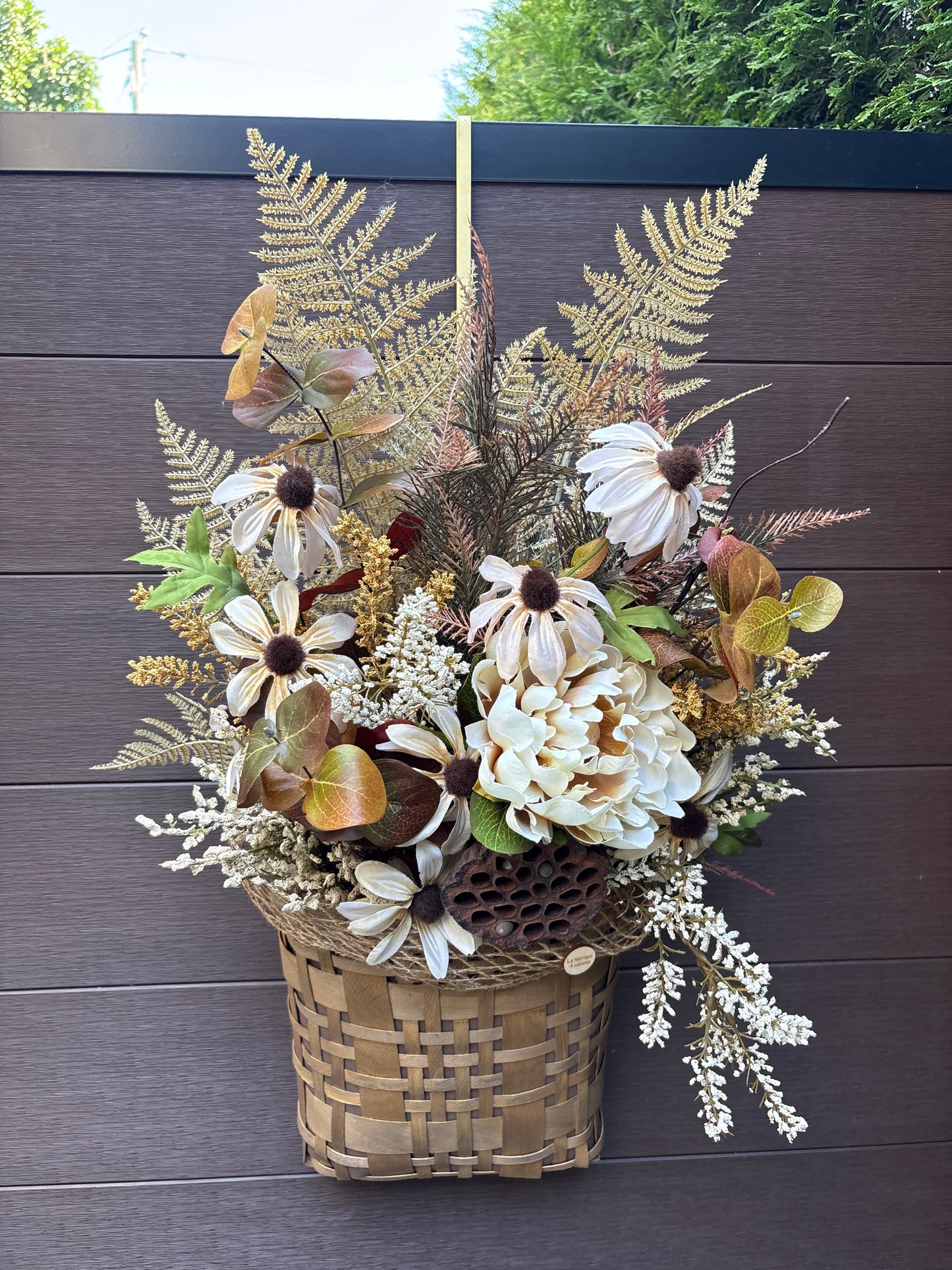 Arrangement floral d’automne dans un panier en osier suspendu.