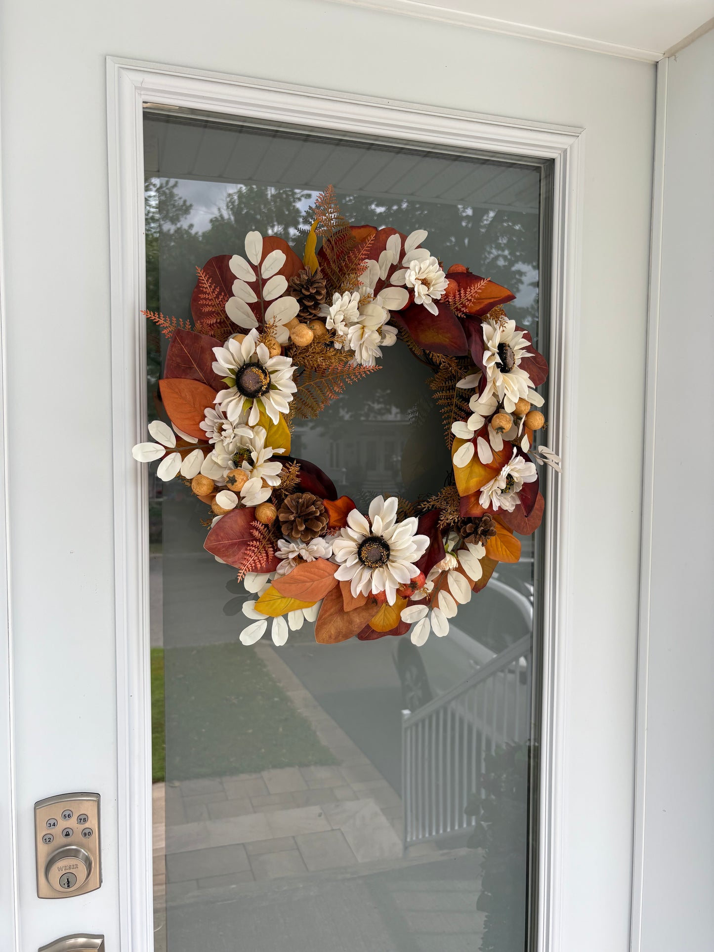 Couronne d’automne aux fleurs blanches présentée sur une porte d’entrée