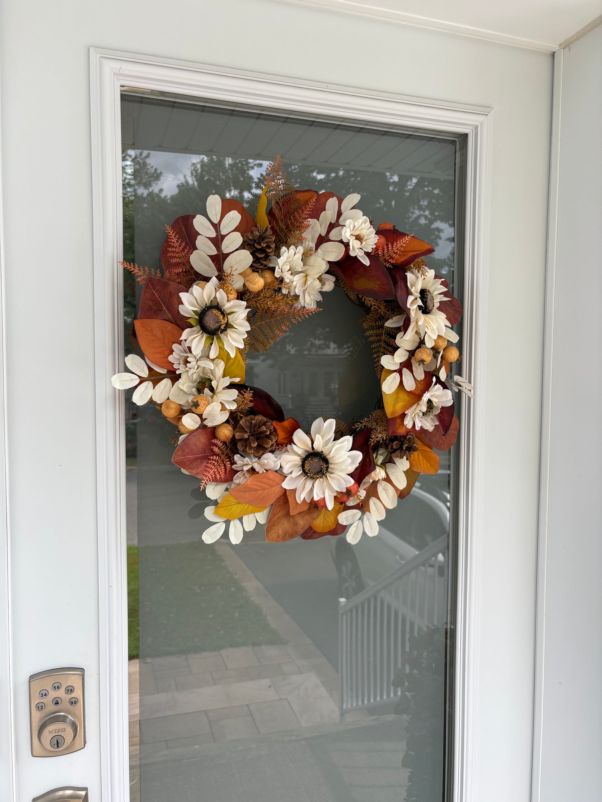 Couronne d’automne aux fleurs blanches présentée sur une porte d’entrée