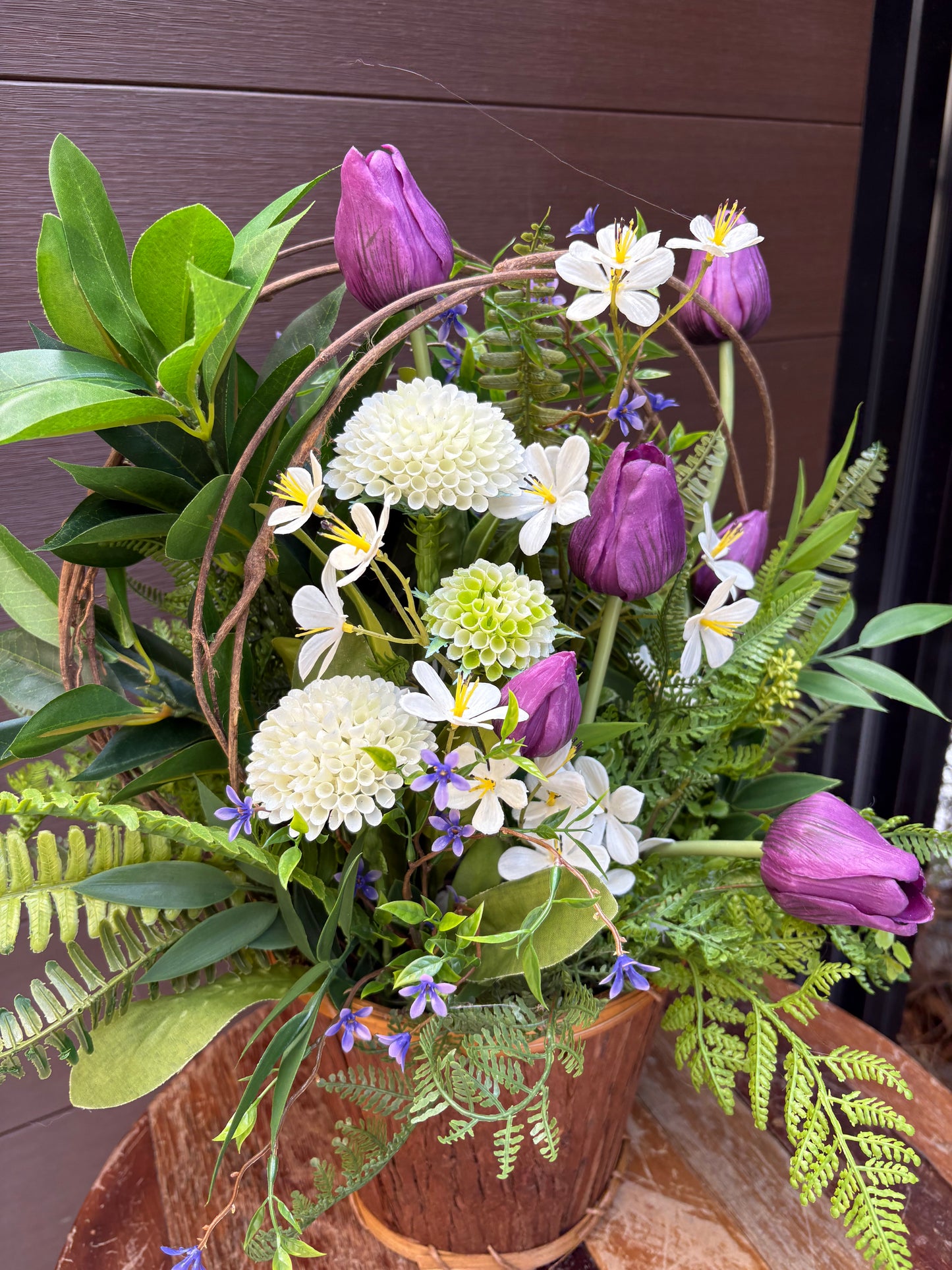 Arrangement floral en pot effet bois avec tulipes mauves et verdure champêtre