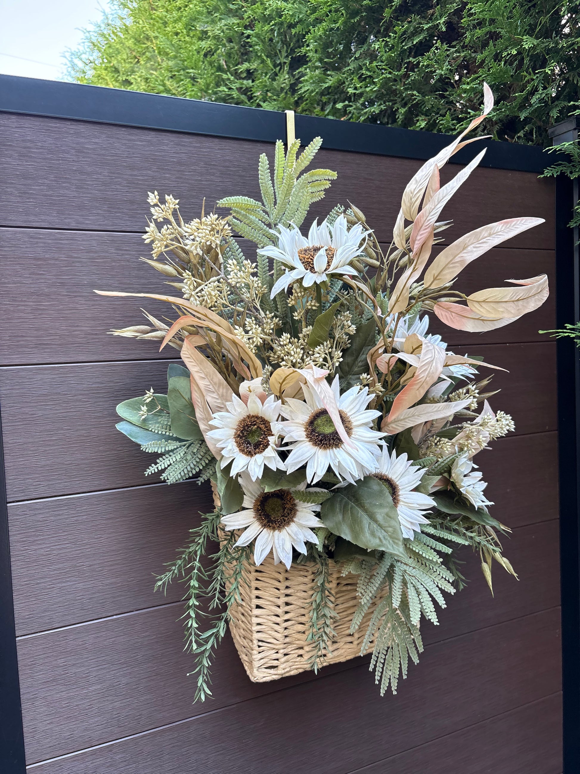 Panier en osier décoré de tournesols blancs et de feuillages artificiels