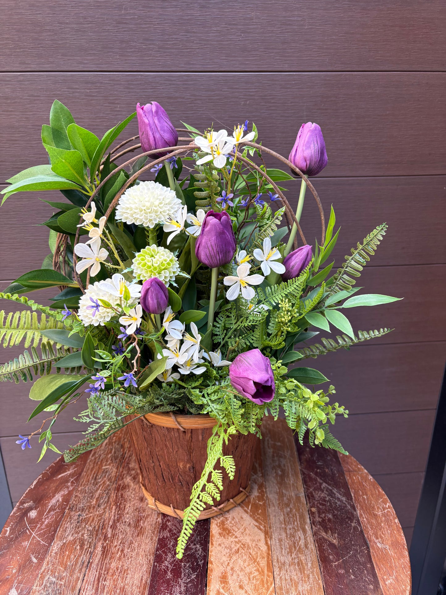 Arrangement floral en pot effet bois avec tulipes mauves et verdure champêtre
