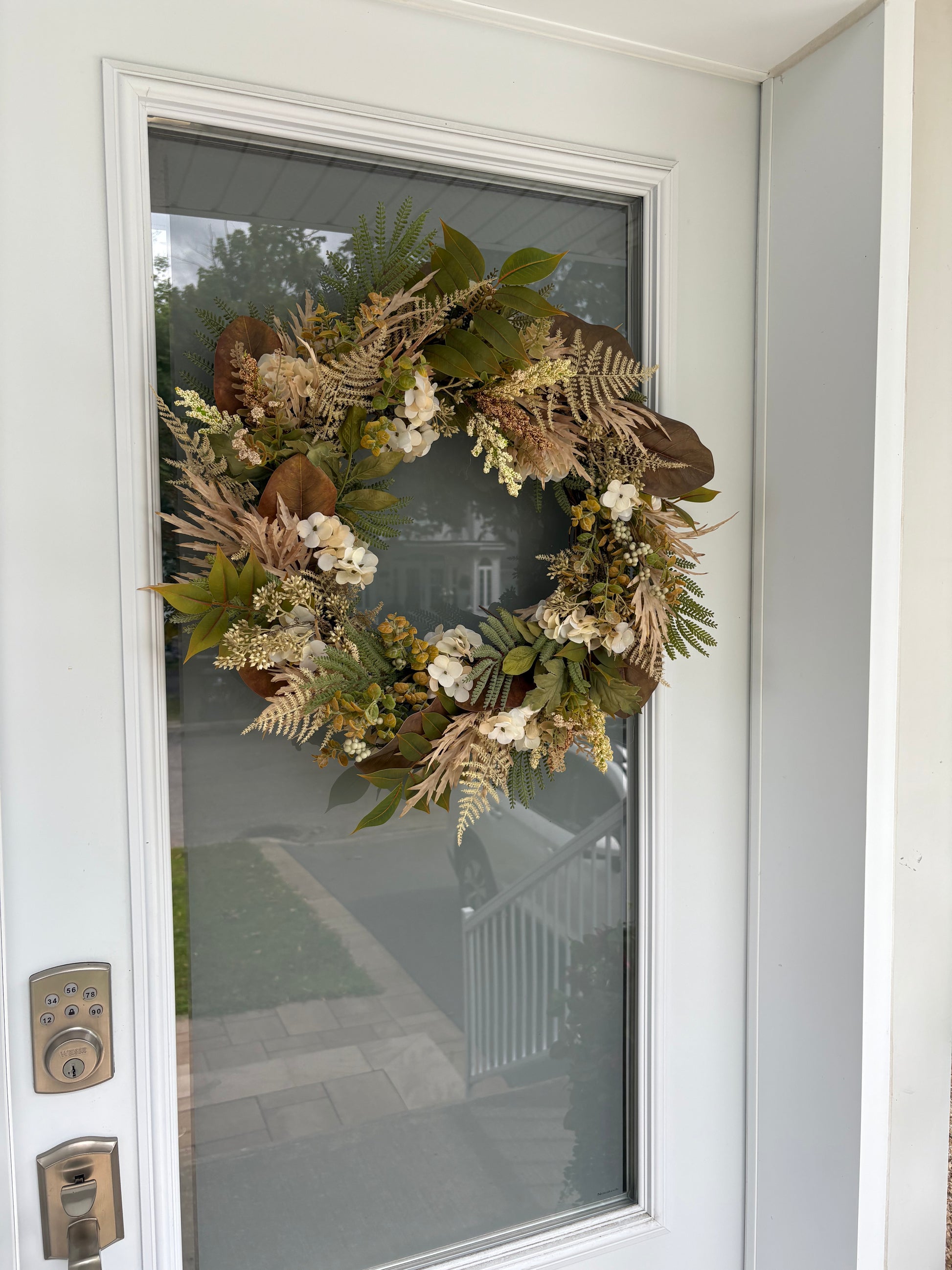 Couronne beige et verte installée sur une porte extérieure abritée