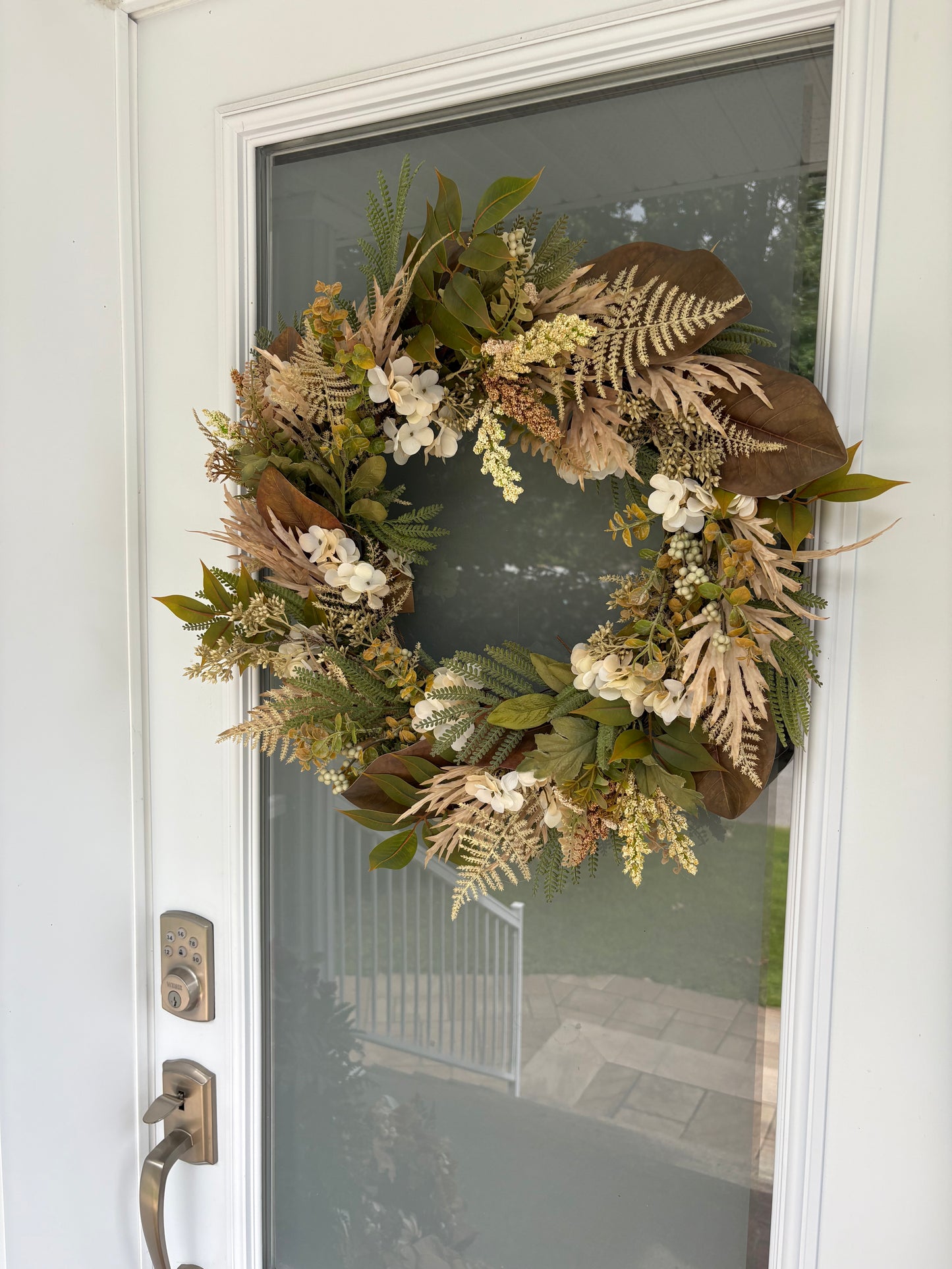 Couronne florale beige et verte sur une porte d’entrée