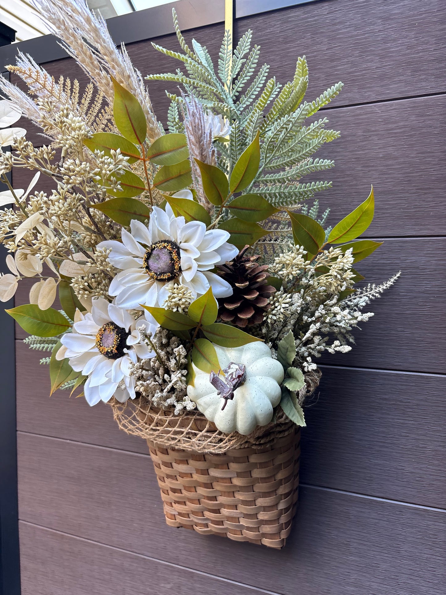 panier en osier garni de fleurs blanches et feuillages automnaux