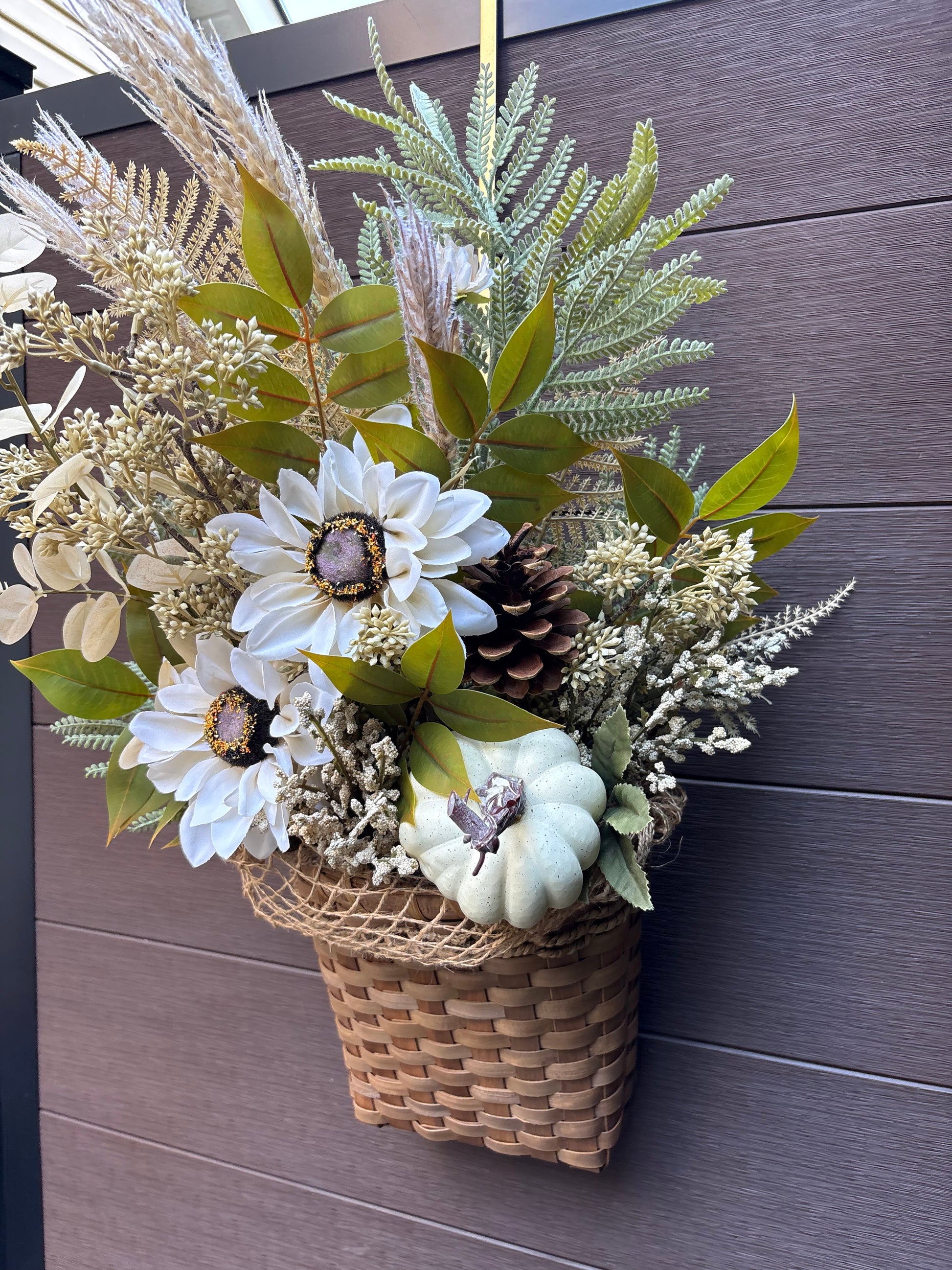 panier en osier garni de fleurs blanches et feuillages automnaux