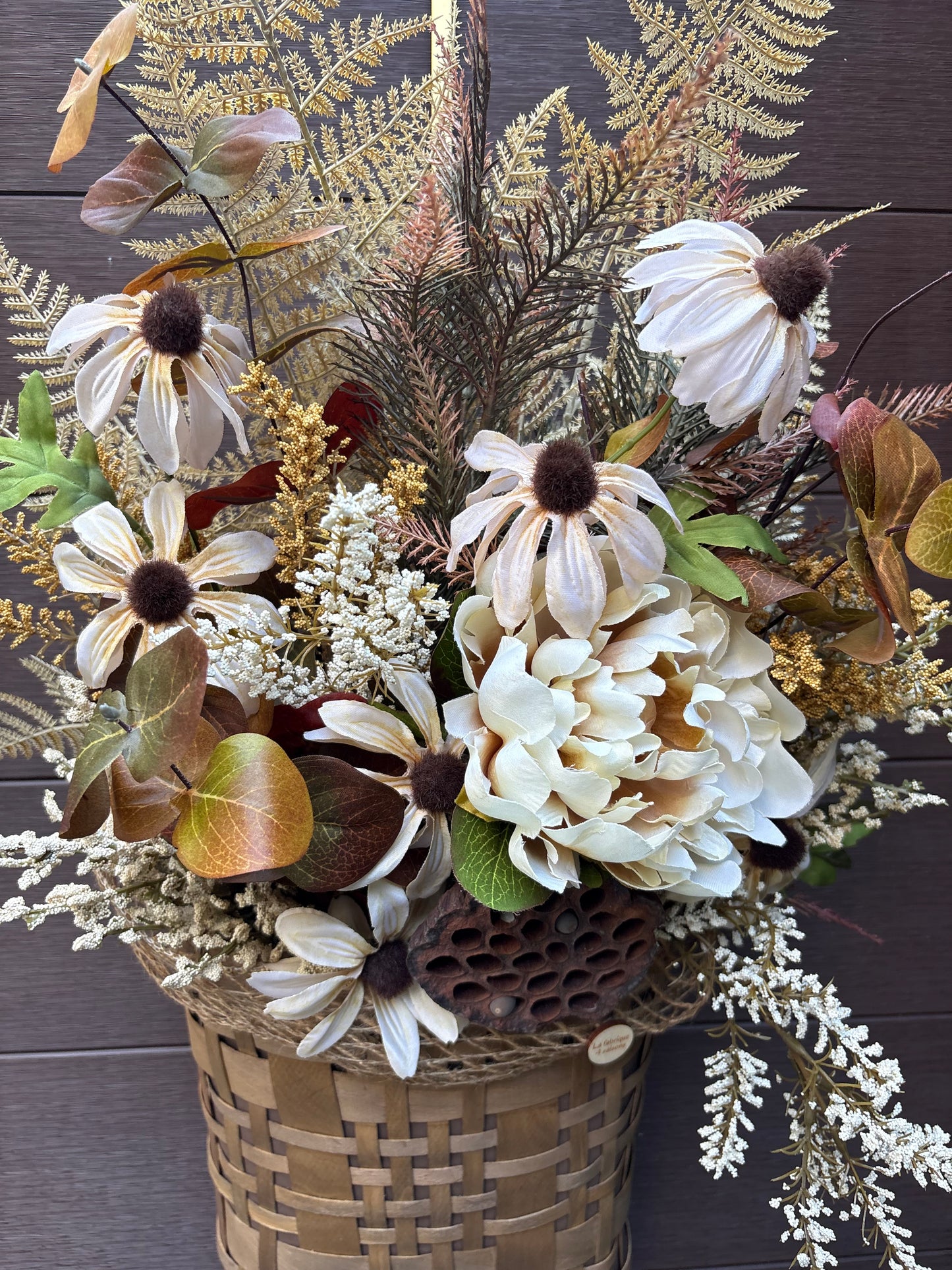 Arrangement floral d’automne dans un panier en osier suspendu.