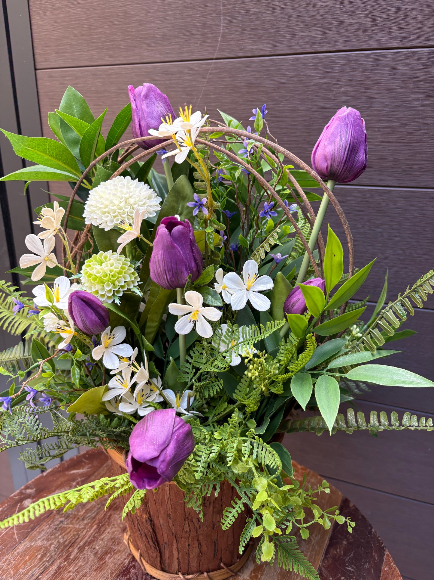 Arrangement floral en pot effet bois avec tulipes mauves et verdure champêtre