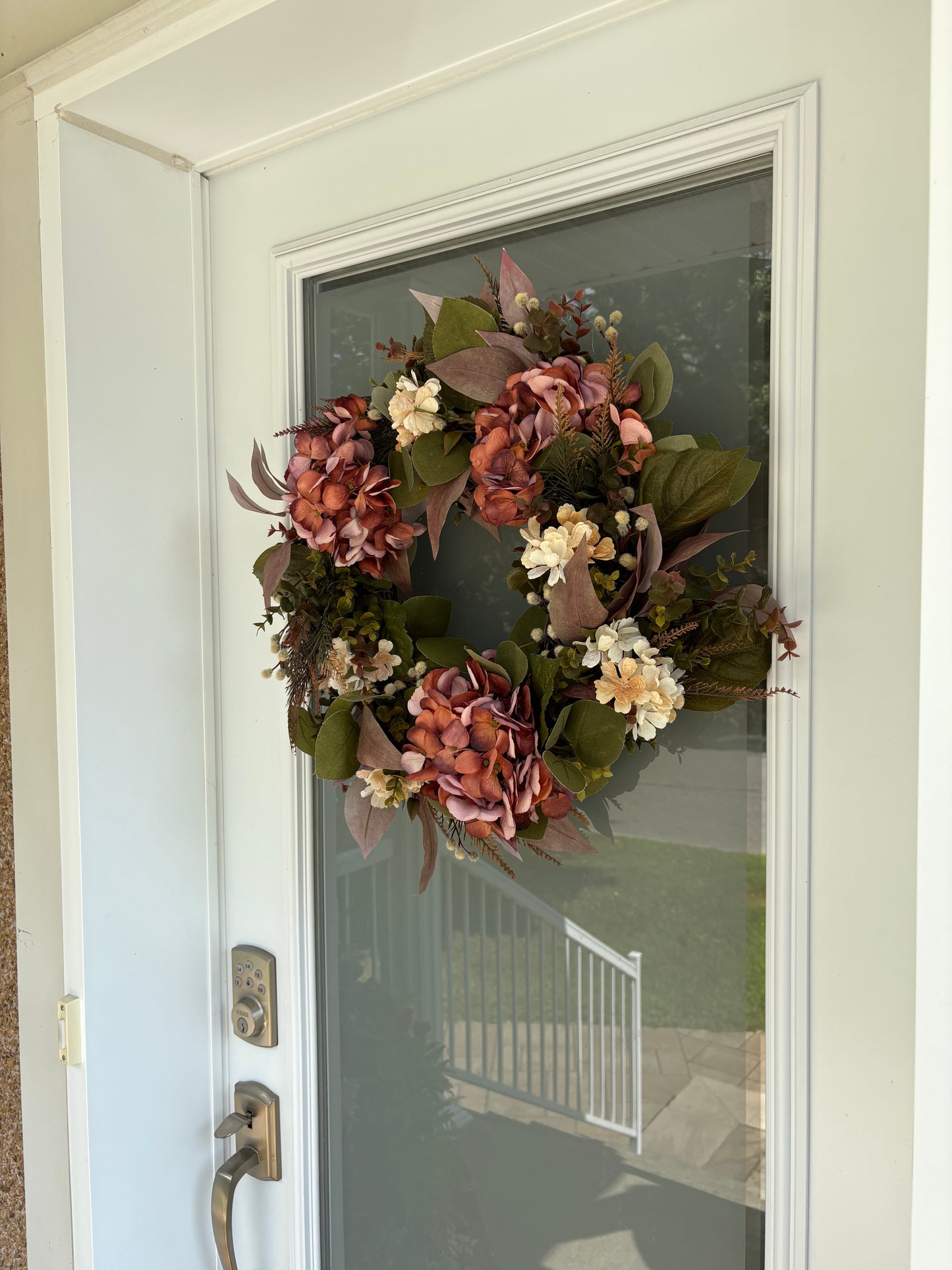 Décoration de porte automnale avec fleurs roses, corail et crème.