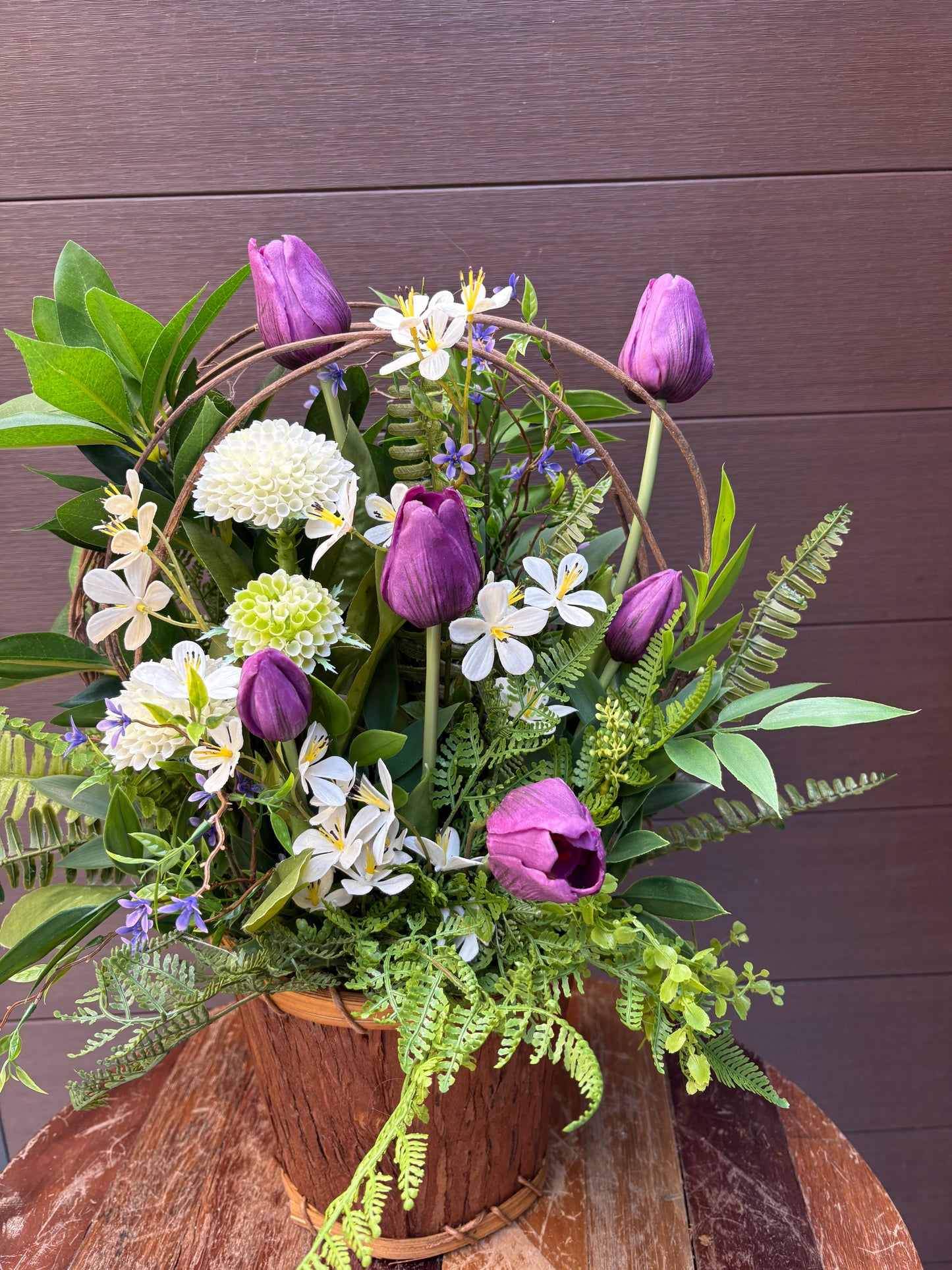 Arrangement floral en pot effet bois avec tulipes mauves et verdure champêtre